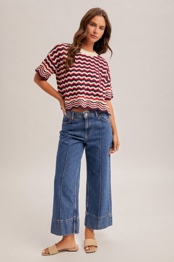 Woman wearing a striped sweater and blue jeans on a plain background