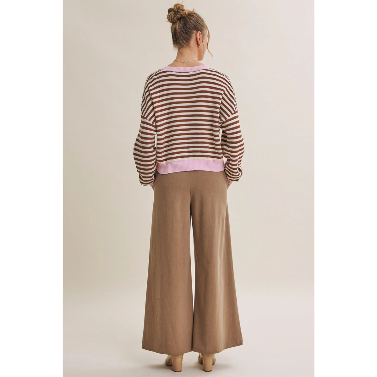 Back view of relaxed brown and cream striped cardigan with pink neckline and hem
