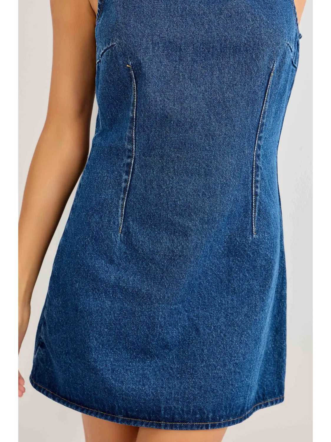 Close-up of curved contour seams on blue denim mini dress