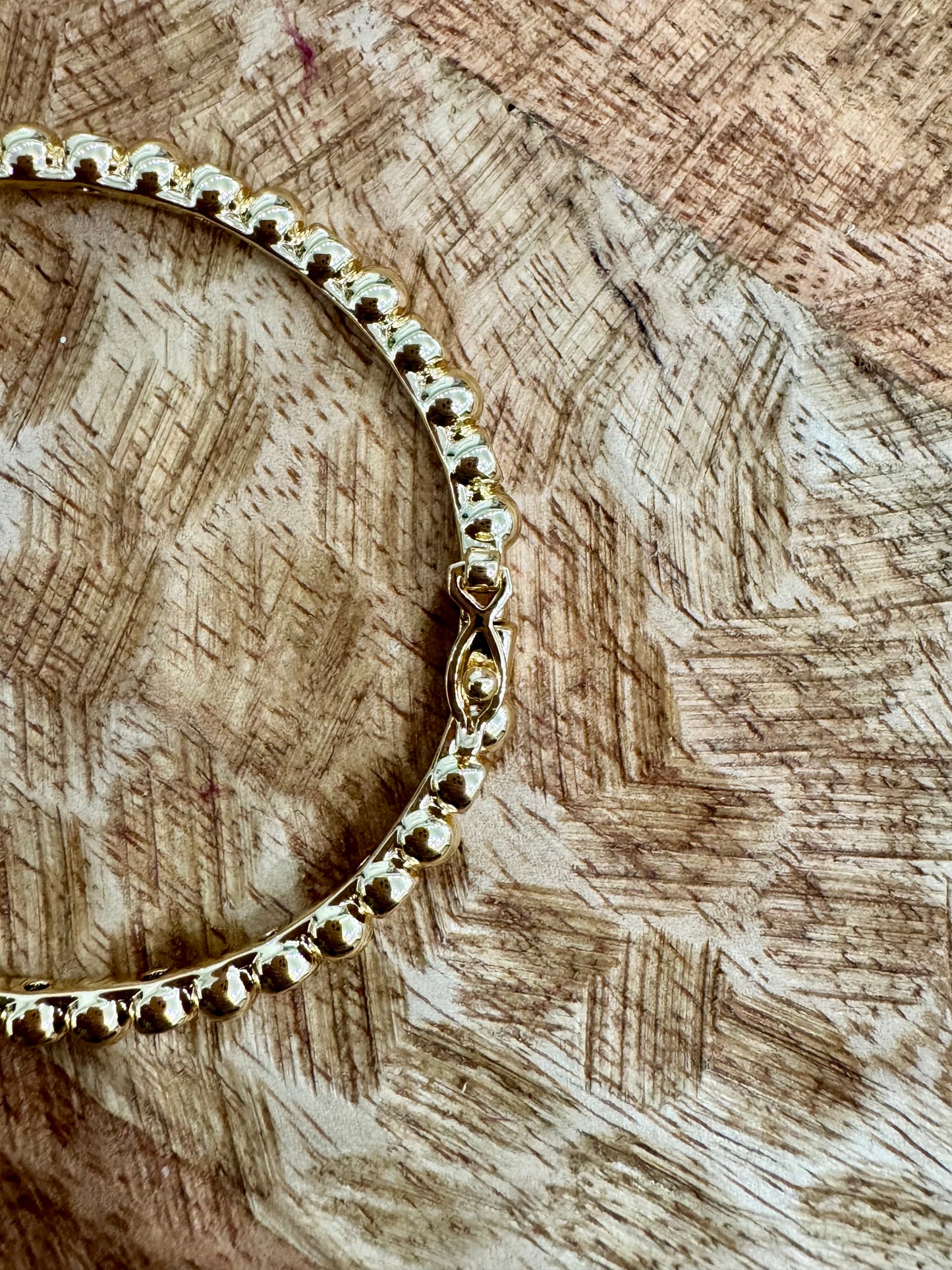 Gold bracelet on a wooden surface