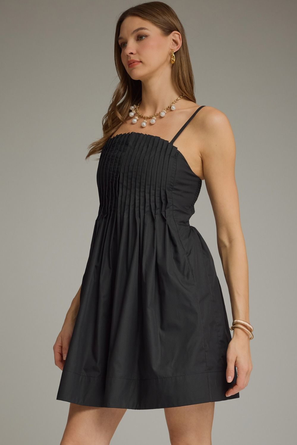 Black pleated sleeveless mini dress with a square neckline and gathered A-line skirt