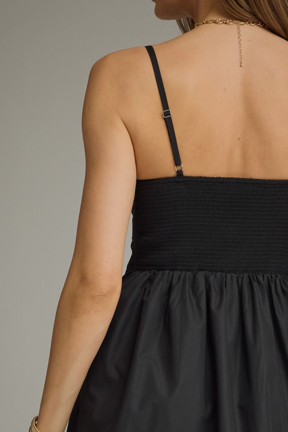 Black pleated sleeveless mini dress with a square neckline and gathered A-line skirt