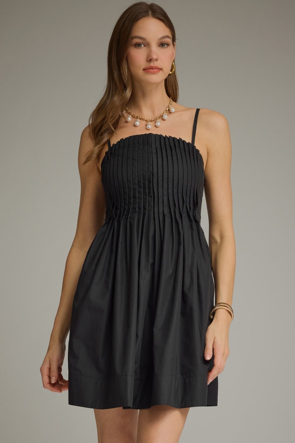 Black pleated sleeveless mini dress with a square neckline and gathered A-line skirt