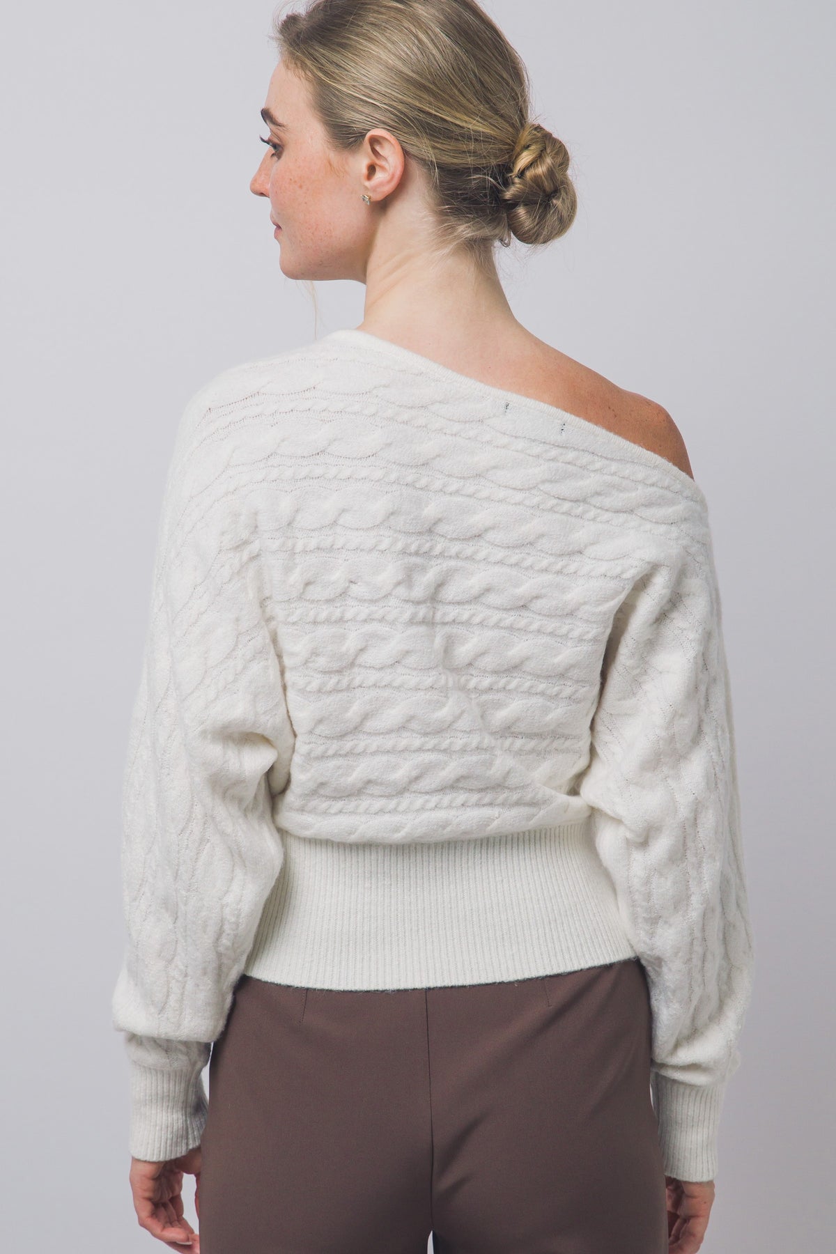 Back view of ivory cable-knit off-shoulder sweater