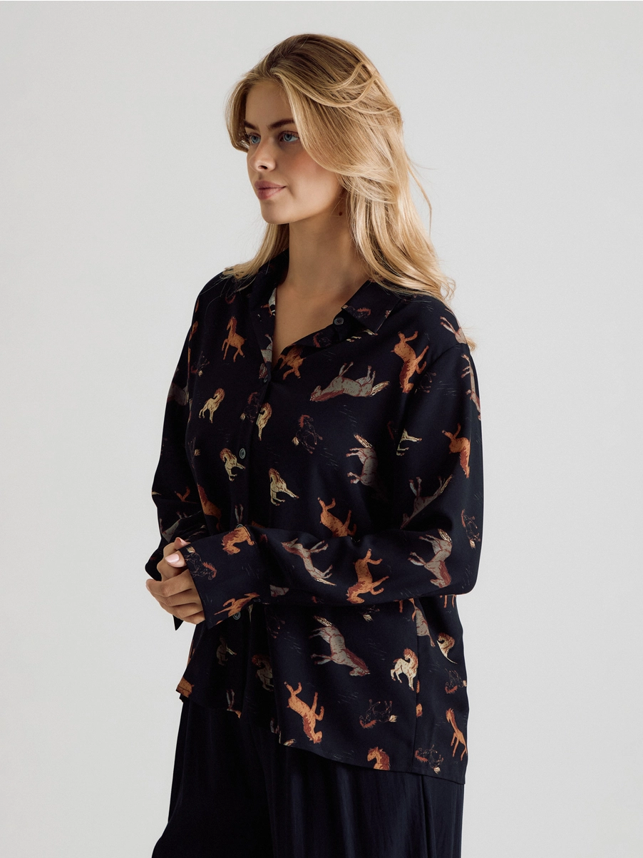 Angled view of black horse-print long-sleeve blouse