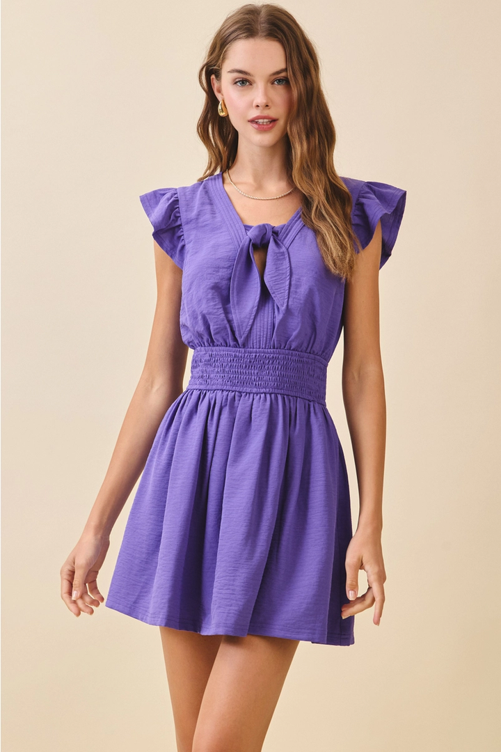 Model wearing purple smocked tie mini dress