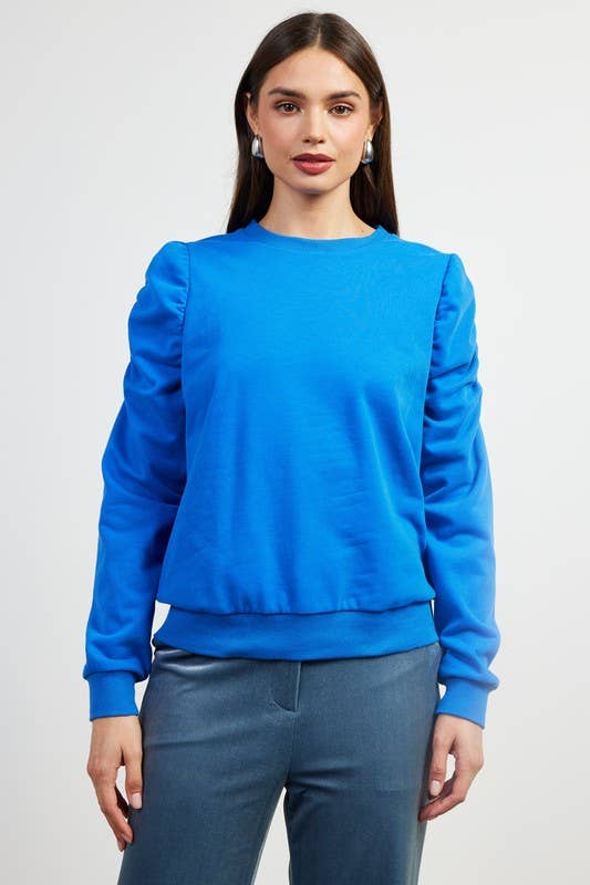 Model wearing the blue ruched-sleeve knit top
