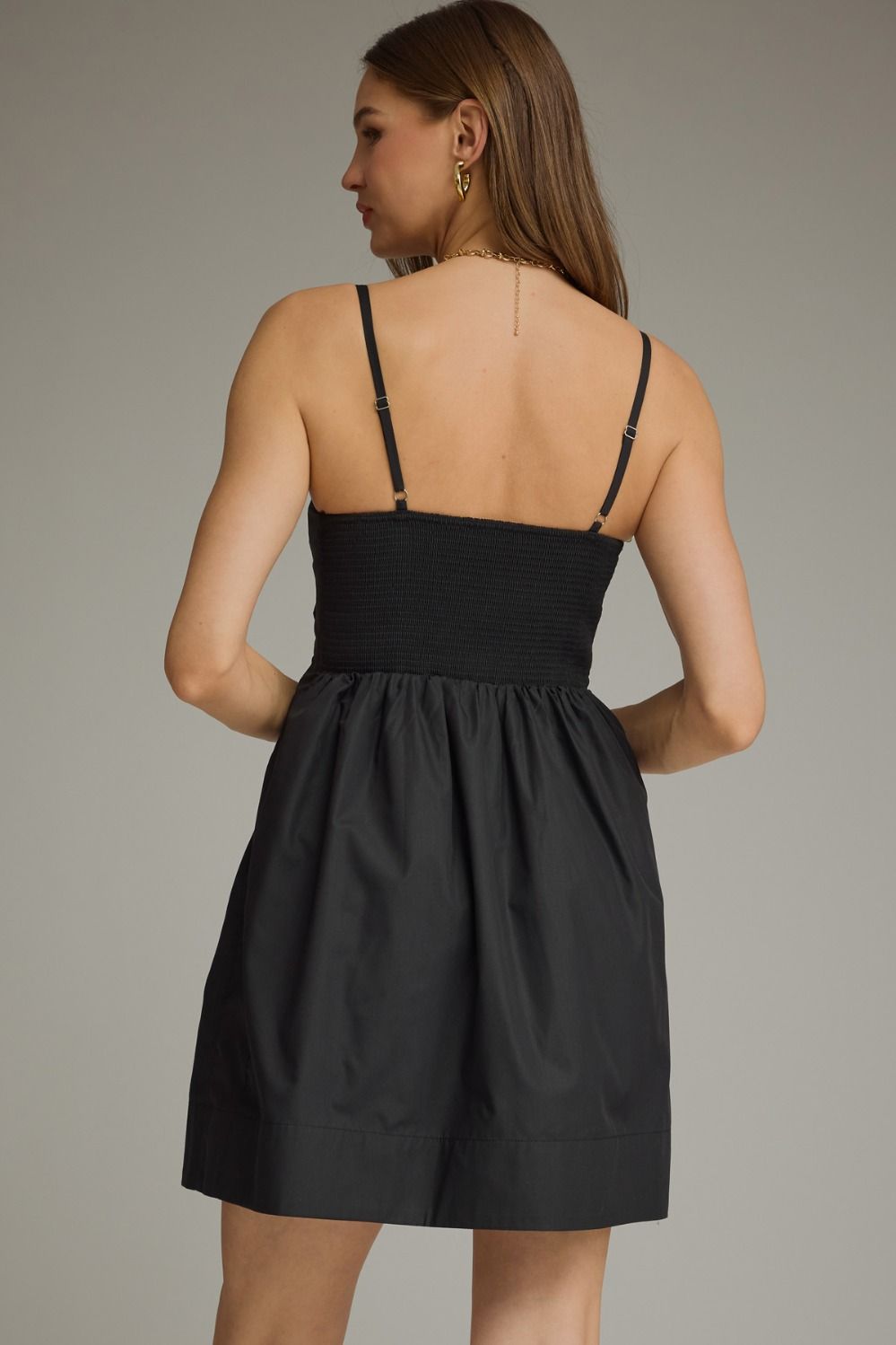 Black pleated sleeveless mini dress with a square neckline and gathered A-line skirt