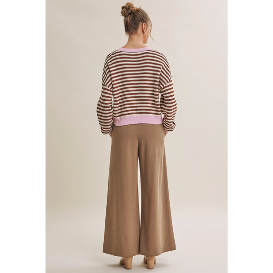 Back view of relaxed brown and cream striped cardigan with pink neckline and hem
