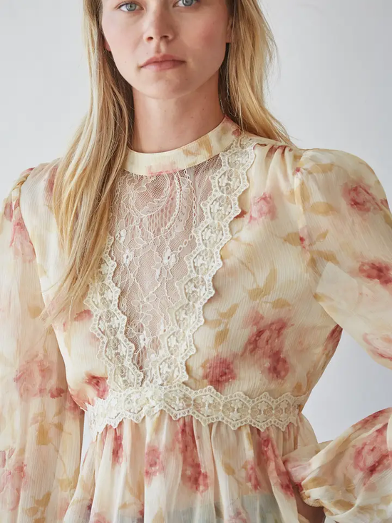 Model wearing cream-and-blush sheer mock-neck top