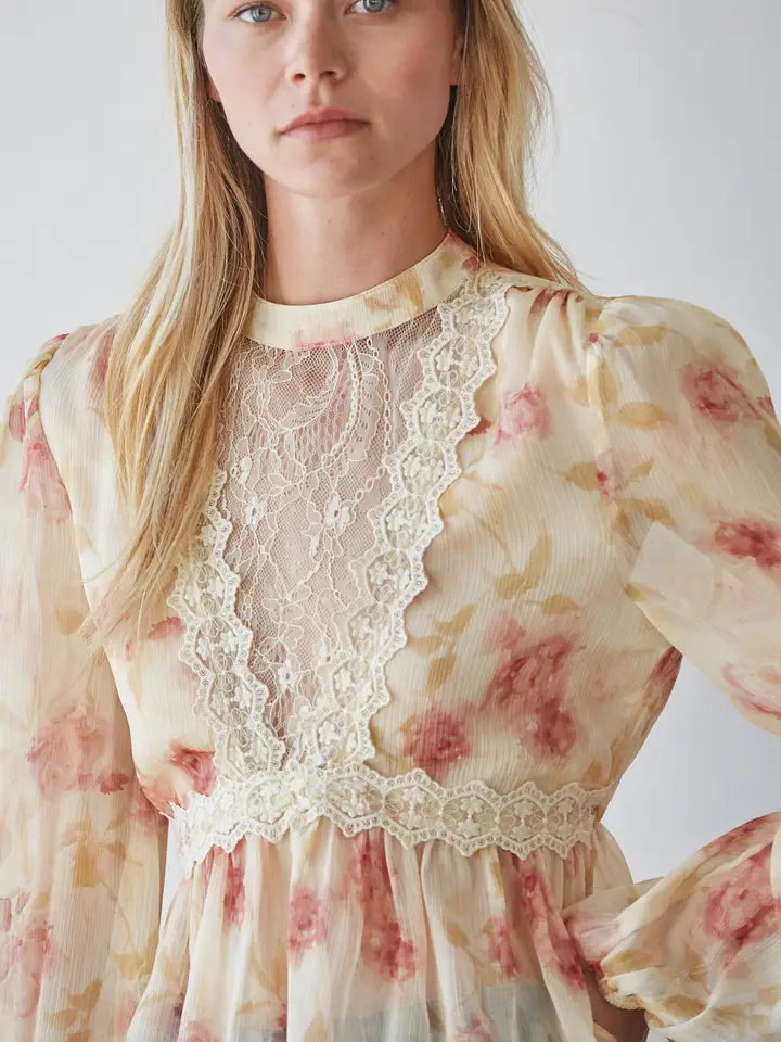 Model wearing cream-and-blush sheer mock-neck top