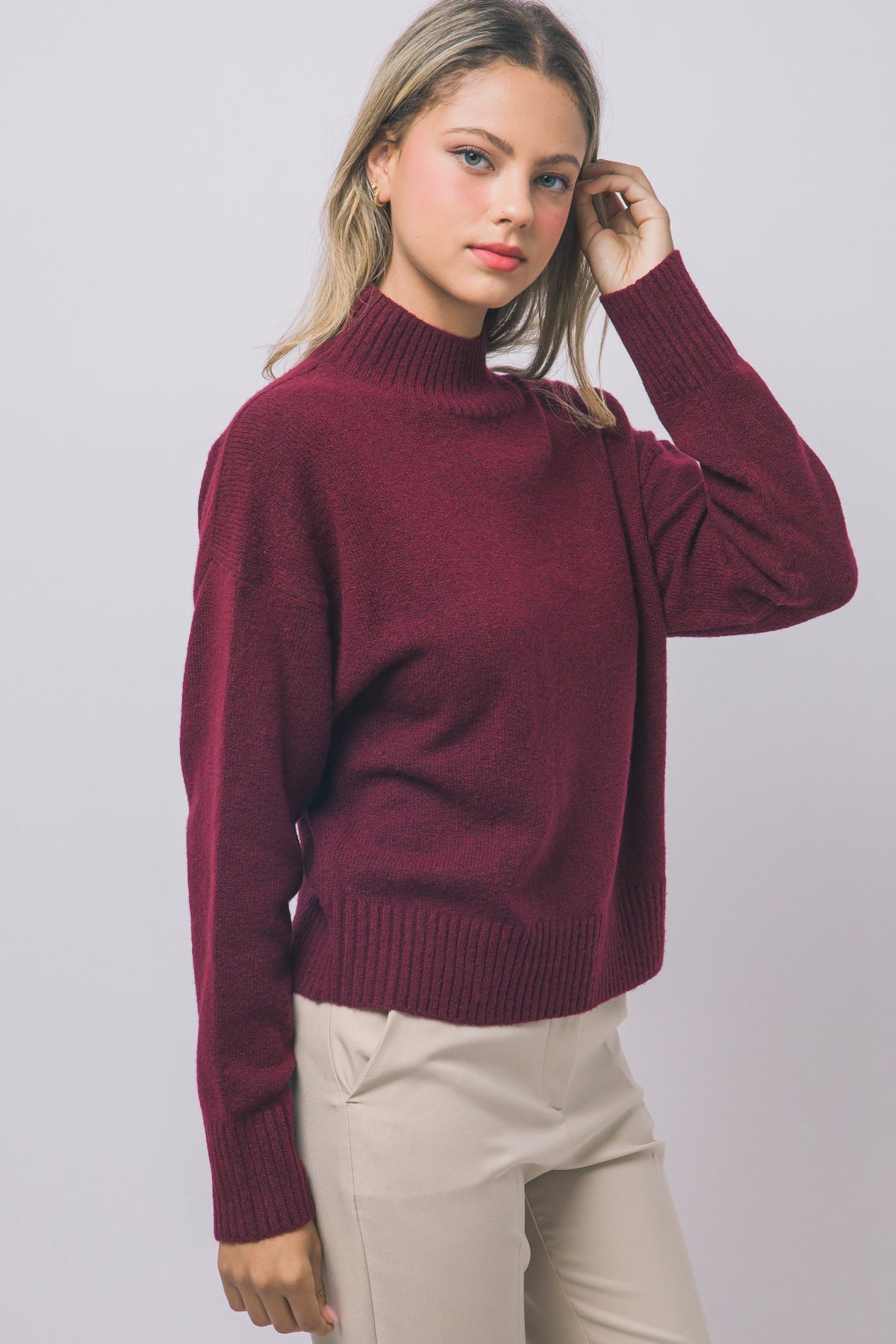 Angled view of red mock-neck sweater with dropped shoulders