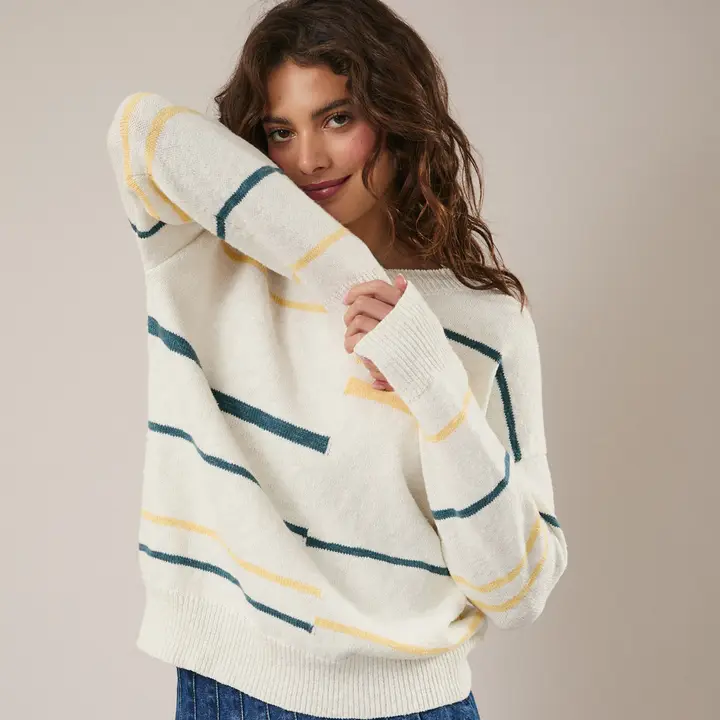 Woman wearing a white sweater with blue and yellow stripes against a beige background