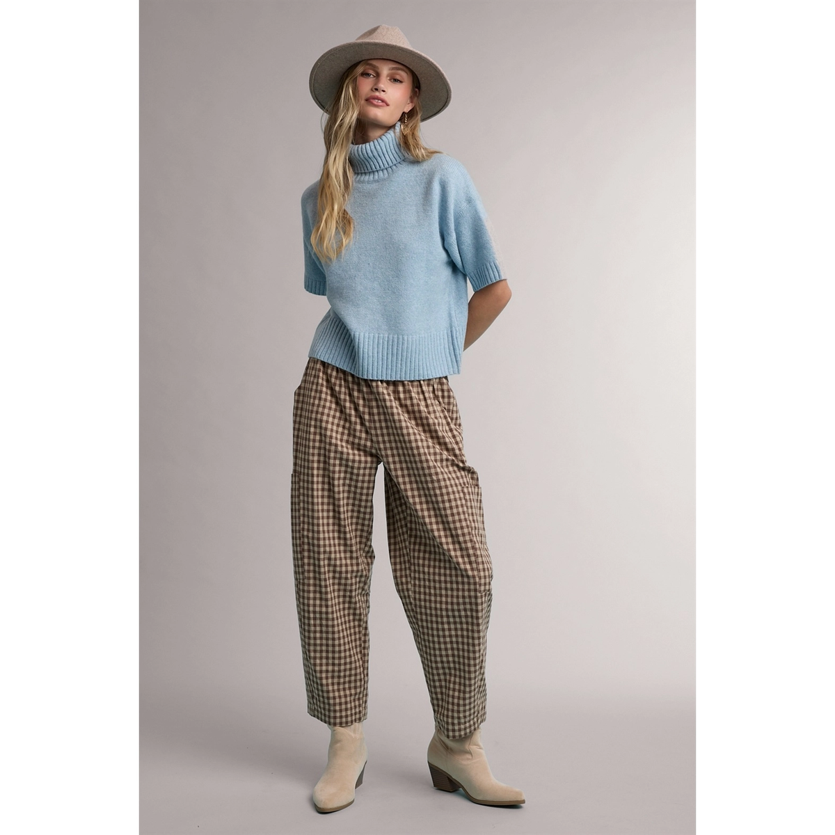 Light blue turtleneck sweater styled with brown check pants